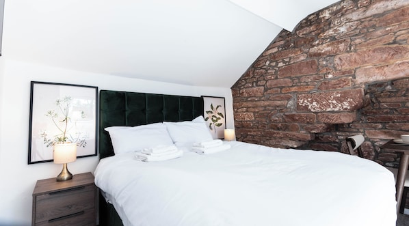 A neatly made bed with white linens, a dark headboard, and a wall-mounted lamp beside it. - The Stanley Arms Hotel by Guestz (Seascale)