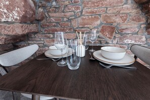 A dining table set with white plates, bowls, glasses, and cutlery, against a brick wall background. - The Stanley Arms Hotel by Guestz (Seascale)