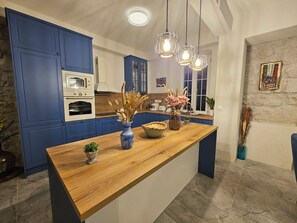 A kitchen with blue cabinets, a wooden countertop, and hanging pendant lights.