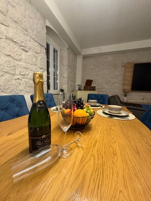 A dining table with a bottle of Paul Louis Brut Blanc de Blanc, a glass, and a fruit bowl.