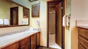 A bathroom with a sink, mirror, towel rack, and a shower door. - Forest Condominiums (Keystone)
