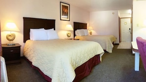A hotel room with two beds, each with a headboard, bedside lamps, and a framed picture on the wall. - Key West Inn Pensacola (Pensacola)
