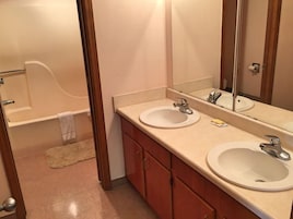 A bathroom with two sinks, a mirror, and a bathtub.