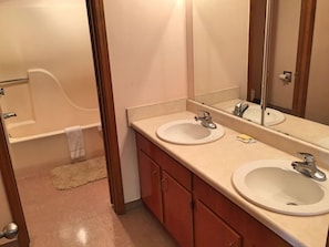 A bathroom with two sinks, a mirror, and a bathtub. - Key West Inn Pensacola (Pensacola)