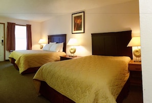 A hotel room with two beds, each with a headboard and bedside lamps. - Key West Inn Pensacola (Pensacola)