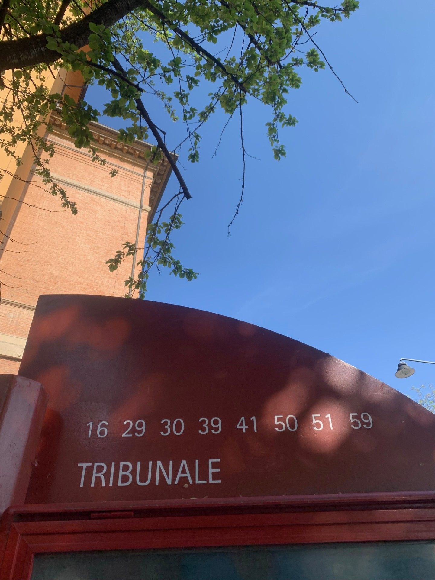 Un edificio con una insegna curva che mostra una serie di numeri e la parola 'TRIBUNALE' in basso.