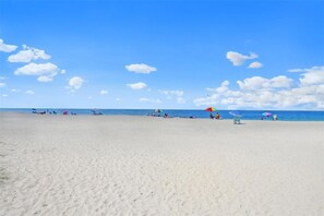 Ein Strand mit blauem Himmel und einigen Personen und Sonnenschirmen.