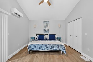 Ein Schlafzimmer mit einem Bett, einem Deckenventilator, einer Klimaanlage, einem Gemälde und einem Kleiderschrank.