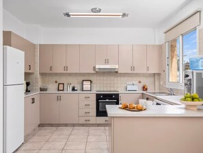 Eine moderne Küche mit hellen Schränken, einem eingebauten Backofen und einem Fenster für natürliches Licht.