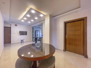 A modern dining area with a round table, recessed ceiling lights, and a wooden door. - Spirit of Amman (Amman)