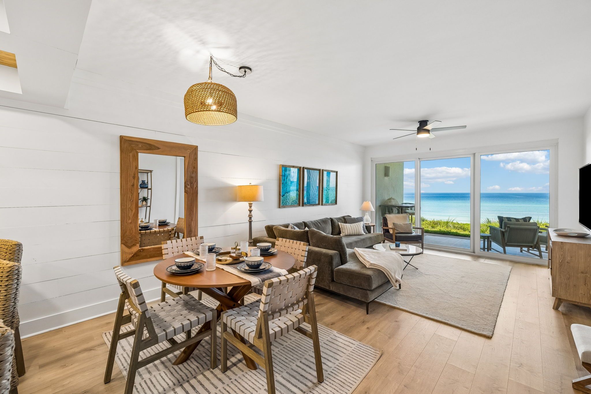 A spacious living area with a dining table, sofa, and a view of the ocean.