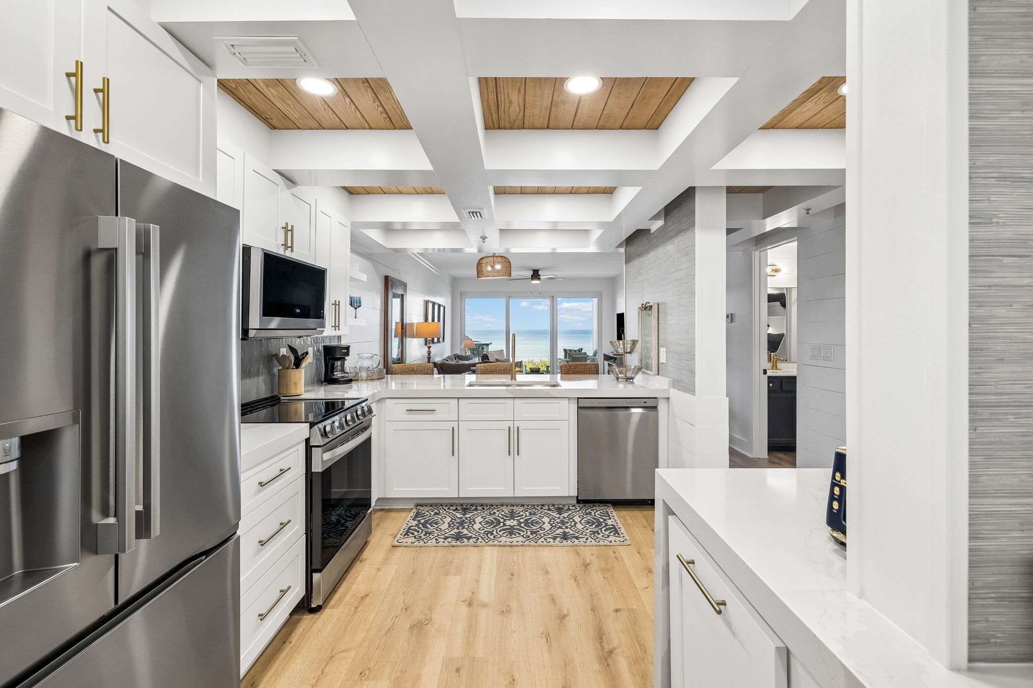A modern kitchen with stainless steel appliances, white cabinetry, and a wooden ceiling.