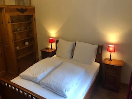 Un dormitorio con cama de madera, dos mesitas de noche con lámparas y un armario de madera.