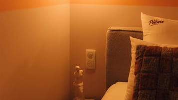Une chambre d’hôtel comprenant un lit, une table de chevet, un luminaire fixé au mur et un objet décoratif.