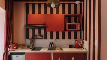 Une cuisine avec des placards rouges, un four à micro-ondes, une bouilloire et une machine à café.