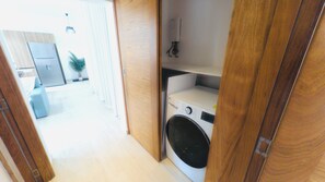 A laundry area with a washing machine and a drying rack.