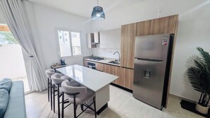A modern kitchen with a central island, stainless steel appliances, and a dining area with bar stools.