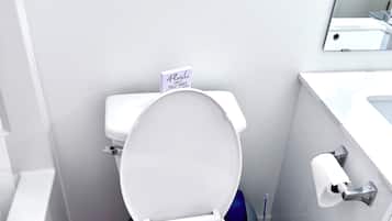 A modern bathroom with a white toilet, a toilet paper holder, and a blue toilet brush.