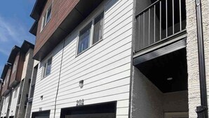 Un immeuble résidentiel à plusieurs étages, doté d’un portail de garage, d’un balcon et d’un numéro de maison bien visible.