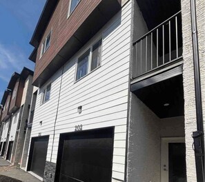 A multi-story residential building with a garage door, a balcony, and a visible address number. - Cozy Central Winnipeg Main Floor Suite – Private & Quiet (Winnipeg)