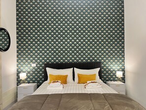 A hotel room with a patterned wallpaper, a black headboard, two bedside tables with lamps, and a bed with a brown duvet. - Vatican Design Near Metro Line A (Roma)