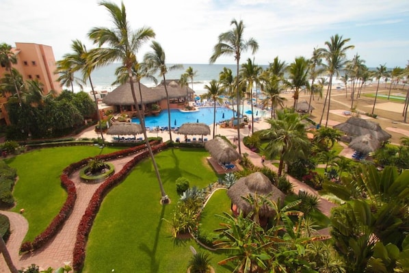 A resort with a swimming pool, palm trees, and a beach view. - Torres Mazatlan Condominiums (Mazatlán)