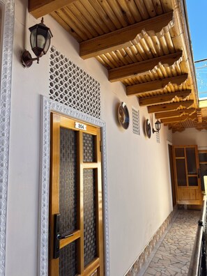 A building entrance with a wooden door labeled '204', a patterned wall, and a tiled floor. - ANIS-PARI Hotel (Bukhara)