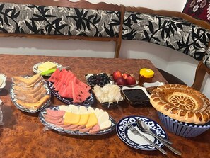 Ein Tisch mit verschiedenen Speisen, darunter Sandwiches, Früchten und einem Kuchen.