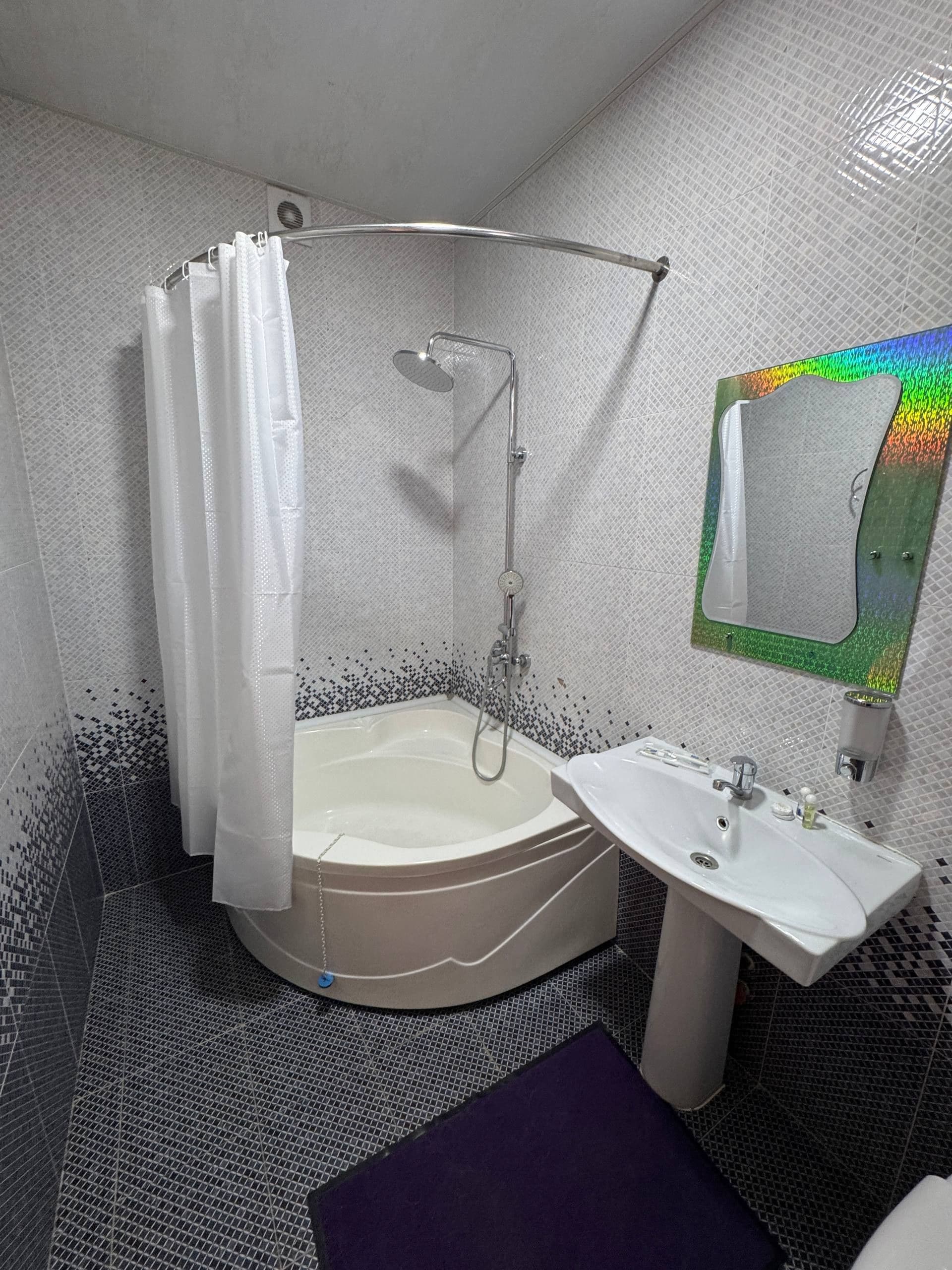 A bathroom with a shower, a sink, and a mirror.