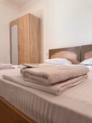 A neatly made bed with a folded blanket and a wooden wardrobe in the background. - ANIS-PARI Hotel (Bukhara)