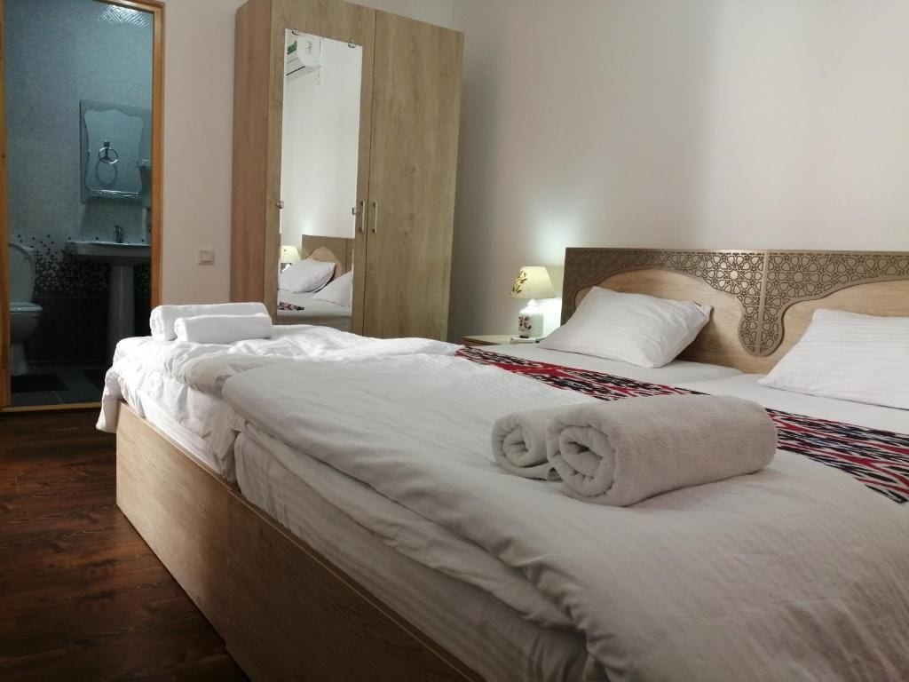 A hotel room with a wooden bed, a nightstand with a lamp, and a wardrobe.