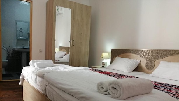 Une chambre d’hôtel avec un lit en bois, une table de chevet avec une lampe et une armoire.
