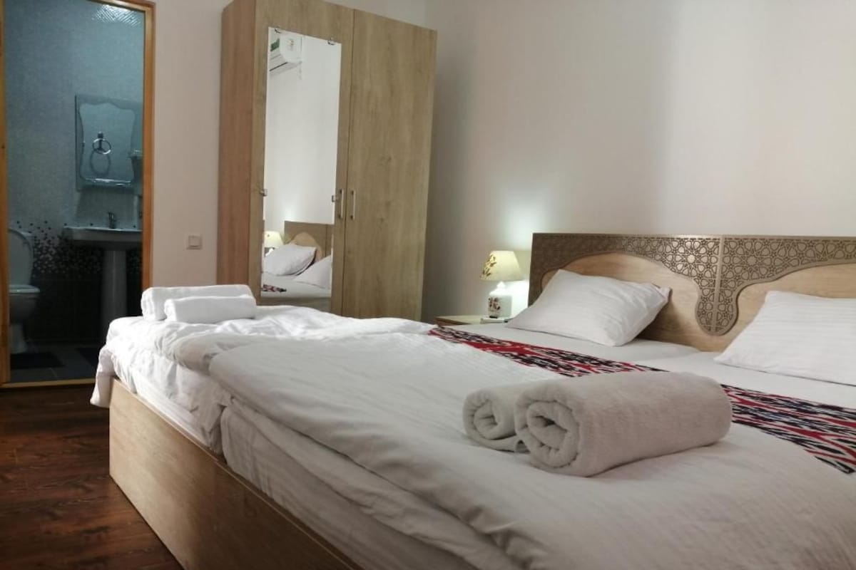 Une chambre d’hôtel avec un lit en bois, une table de chevet avec une lampe et une armoire.