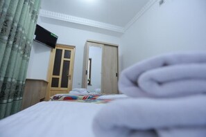Ein Zimmer mit einem Bett, einem Schrank, einer Tür und einem Vorhang.