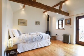 Un dormitorio con cama, radiador, ventana y chimenea.