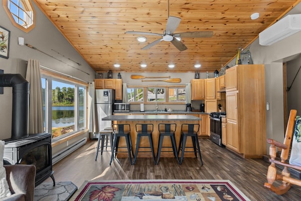 A kitchen with a central island, wooden cabinets, a stove, and a view of a lake.