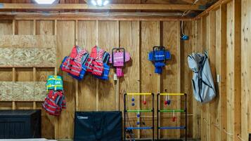 A room with wooden walls, a ceiling fan, and various items including life jackets, a bag, and a climbing wall.