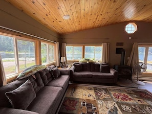 Ein gemütliches Wohnzimmer mit einem großen Ecksofa, einem Kamin und Blick ins Freie.