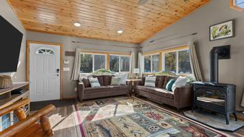 A cozy living room with a fireplace, two sofas, a television, and a patterned rug.