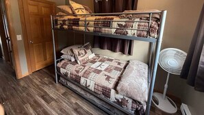 Un lit superposé avec un ventilateur au plafond, une porte et un ventilateur au sol.