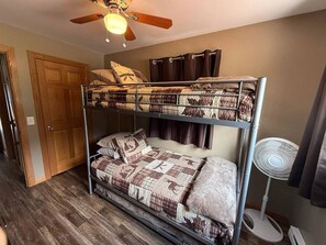 Ein Etagenbett mit Deckenventilator, einer Tür und einem Standventilator.