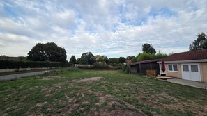 A residential backyard with a grassy lawn, a wooden deck, and a detached garage.
