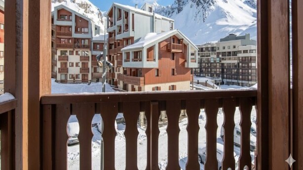 Un complejo turístico de montaña con edificios de varios pisos, balcones y un paisaje nevado.