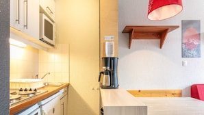 Una kitchenette pequeña equipada con microondas, estufa y cafetera.