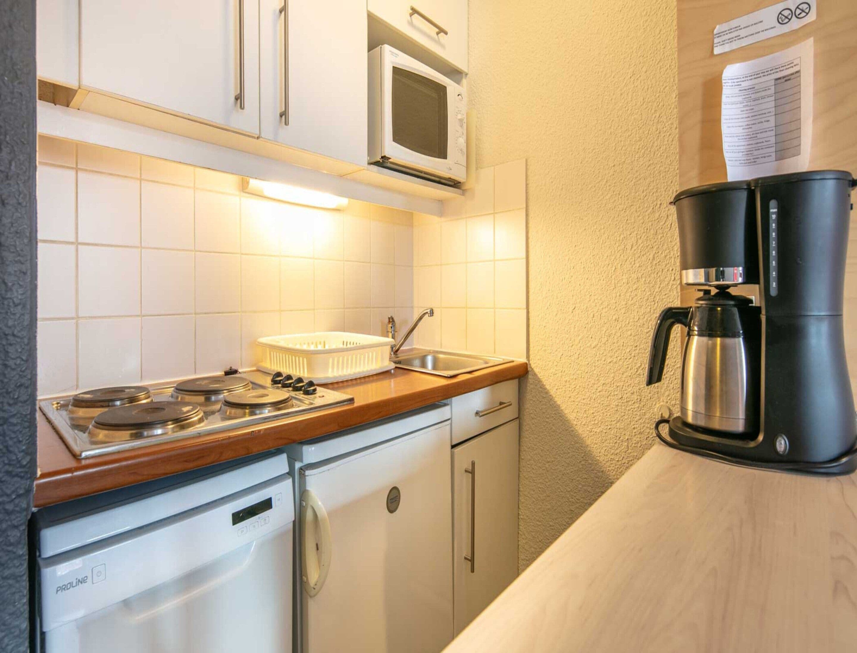 Una cocina compacta equipada con estufa, microondas y cafetera.
