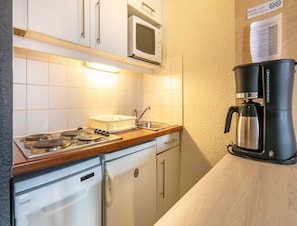 A compact kitchen with a stove, microwave, and coffee maker. - Alpine Stay With Balcony in Tignes (Tignes)