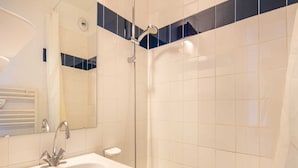 Un baño con lavamanos blanco, espejo, ducha y bañera.