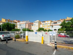 Ein geschlossenes Wohngebiet mit mehreren Mehrfamilienhäusern, blauem Himmel und parkenden Autos.