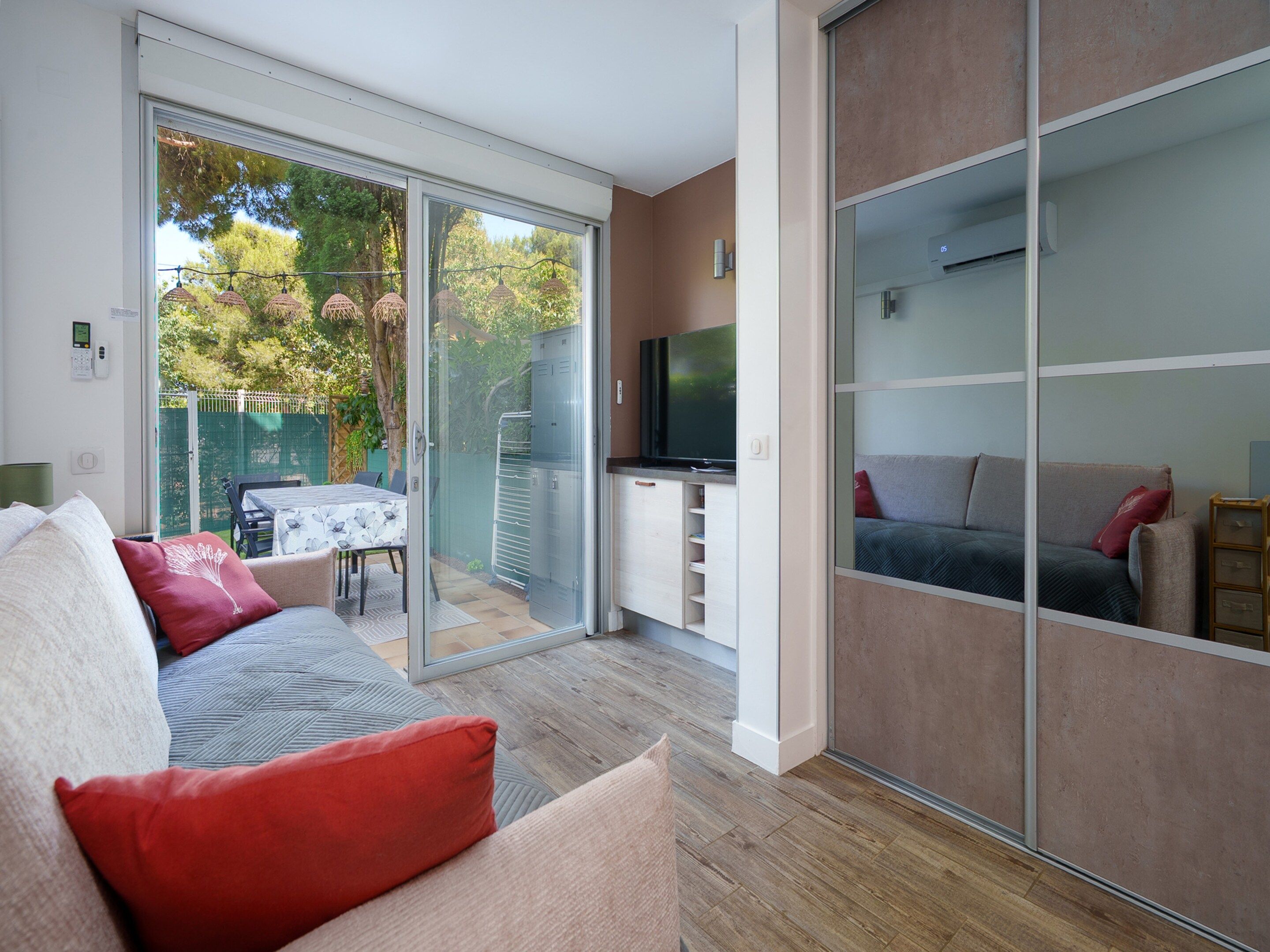 A modern living room with a sofa, a TV, and a sliding glass door leading to an outdoor area.
