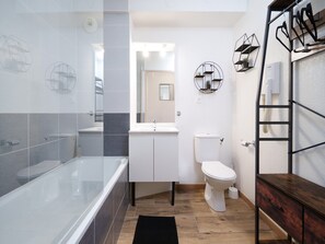Un baño moderno con ducha envuelta en vidrio, inodoro blanco y tocador de madera con espejo.